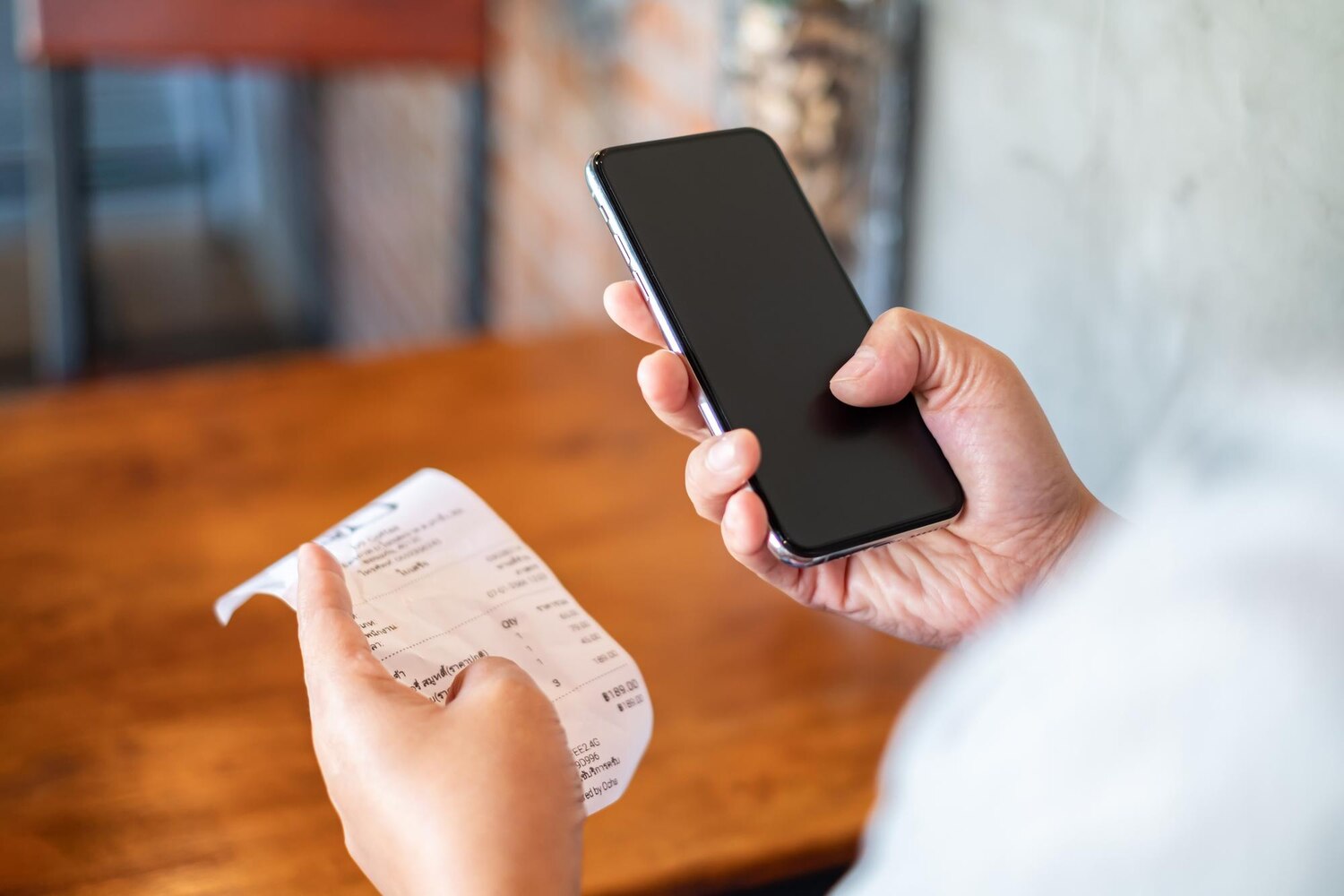 Person holding phone and receipt at a restaurant